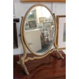 A mahogany oval toilet mirror on skeleton frame, 56cm by 46cm