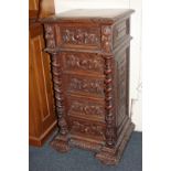 A carved oak narrow chest of drawers, profusely decorated with foliate designs, with overhanging