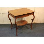 An oak occasional table, with shaped top and oval under shelf, on scroll carved slender cabriole