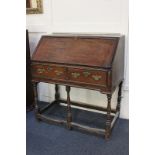 An 18th century oak bureau with fall enclosing fitted interior of drawers, pigeon holes and secret