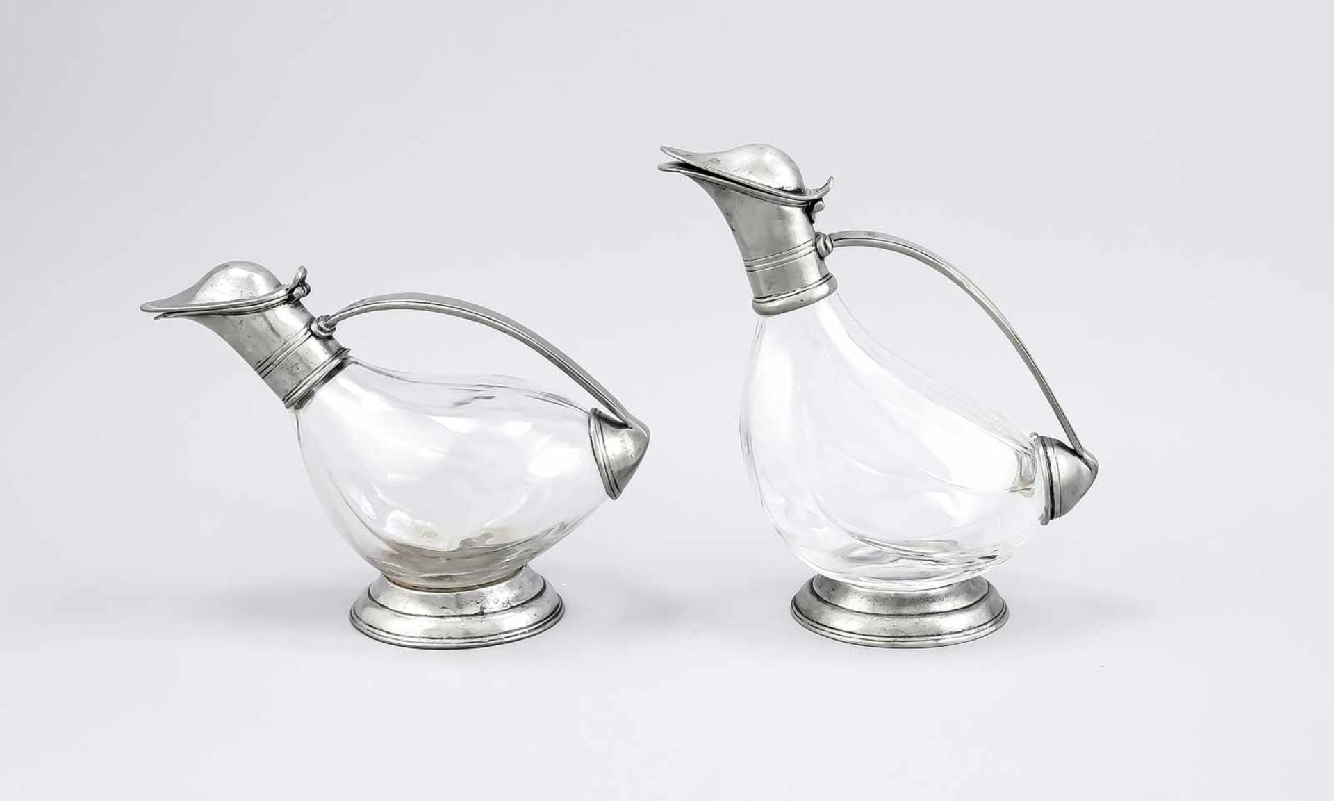 Zwei Dekantierkaraffen, 19. Jh., in Form von Enten, Korpus klares Glas mit Zinnstand,-henkel und -