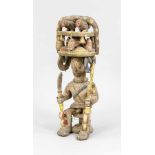 Figur eines Sitzenden mit Kopfaufsatz, Ikenga/Igbo, Nigeria. Holz, z.T. polychromstaffiert.