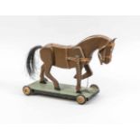 Spielzeug-Pferd, um 1900. Holzpferd, braun lackiert. Leder-Zaumzeug. Echthaarschwanz. Aufgrün