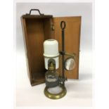 A WOODEN CASED BRASS MICROSCOPE OIL LAMP