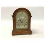 AN OAK CASED CHIMING MANTLE CLOCK WITH A