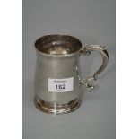 A George III silver mug, baluster form, leaf capped scroll handles, on spreading circular foot,