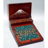 An early 20th century Japanese red lacquer painted writing slope, the hinged lid with black