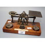 A set of Edwardian brass postal scales, with weights on an oak plinth with ivorine plaque