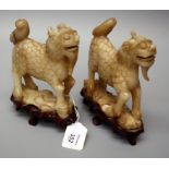 A pair of Chinese carved mutton fat jade kylin, each on a carved wooden base, 14cm