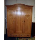 A continental pine armoire, the serpentine cornice over egg and dart frieze and three panelled doors
