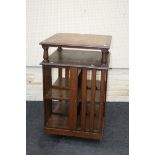 An Edwardian oak library three tier revolving bookcase, with stencilled numbers, slatted sides on