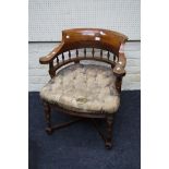 An Edwardian oak Captain's armchair with bow back, spindle splats, button hide overstuffed seat,