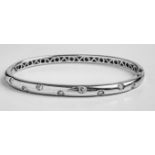 An 18ct white gold and diamond bangle, the plain carved, polished band inset with nine brilliant-cut