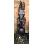 A carved wood garden ornament of the Easter Bunny, standing upon hind legs, with egg at feet, 102cm