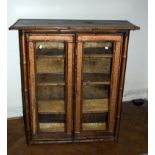 A 19th century bamboo and woven cane bookcase, having a pair of glazed doors enclosing three