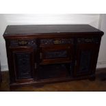 An Edwardian mahogany dresser with carved frieze drawers and cupboards around 'dog kennel' recess,