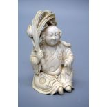A 19th century Chinese carved ivory okimono of a seated robed figure holding a peach bough, 10.5cm