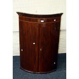 A George III mahogany, boxwood inlaid and strung hanging corner cupboard of bow front form, 105 x