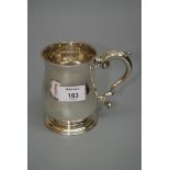 A George III mug, baluster form, with stepped circular skirt foot and leaf-capped scroll handle,