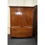 An early 19th century mahogany linen press, the moulded cornice over herringbone frieze and a pair