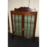 An Edwardian mahogany bow front vitrine, the top with gadrooned edge, over a pair of glazed doors