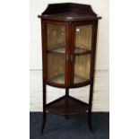 An Edwardian mahogany and strung bow fronted corner vitrine, having a low upstand over a pair of