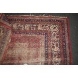 An early 20th century Persian Senneh woven wool rug with repeating leaf forms on a crimson ground,