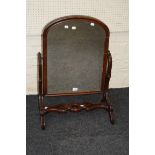 An Edwardian mahogany toilet mirror, the cushion framed arched plate on a pierced support, 82 x