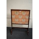 An early Victorian mahogany firescreen with needlework panel