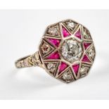 An Art Deco ruby and diamond cluster ring, the central brilliant cut diamond within a border of