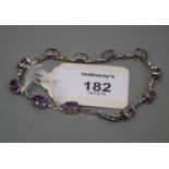 An amethyst line bracelet, with seven oval cut amethysts within claw mounts and scroll links