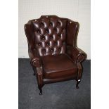 A George III style deep buttoned brown leather upholstered 'hipped' wing chair, with cabriole