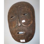 A carved wood African, possibly Dan mask with narrow eyes and pitted outlin, 41cm long