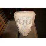 A painted plaster architectural wall bracket with angel detail, 47cm wide