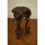 A Colonial hardwood jardiniere stand with elephant head monopodia, each with curling tusks