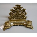 A pierced, cast brass desk stand, with a pair of covered ink wells, on winged cherub feet