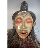 A carved wood African 'Puna' mask with painted face and straw hair, 40cm long