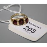 A three stone garnet half-hoop ring, the oval cut garnets with diamond detail and carved 18ct gold