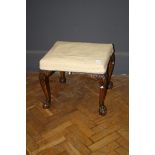 A George III style walnut cabriole legged stool with ball and claw feet, 57cm wide