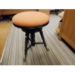 An antique revolving piano stool on metal and glas