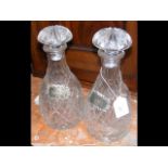 A pair of cut glass decanters with silver labels