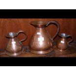 A set of three graduated antique copper jugs