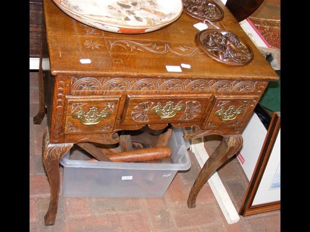 A carved oak lowboy with three drawers to the fron