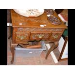 A carved oak lowboy with three drawers to the fron