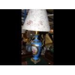 A porcelain and gilt table lamp with hand painted oval panel