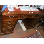 An antique pedestal desk with red leather top and