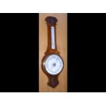 A carved oak barometer/thermometer