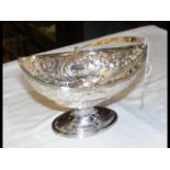 A decorative silver bonbon dish with hinged handle