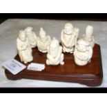 Seven Japanese carved ivory figures on wooden stan