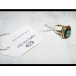 A rectangular green stone dress ring in gold setti